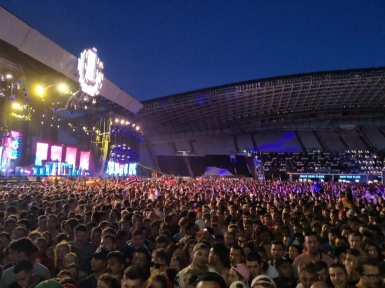 A photo of main stage at Ultra Music Festival Croatia, a large crowd of thousands of people are dancing with their hands up