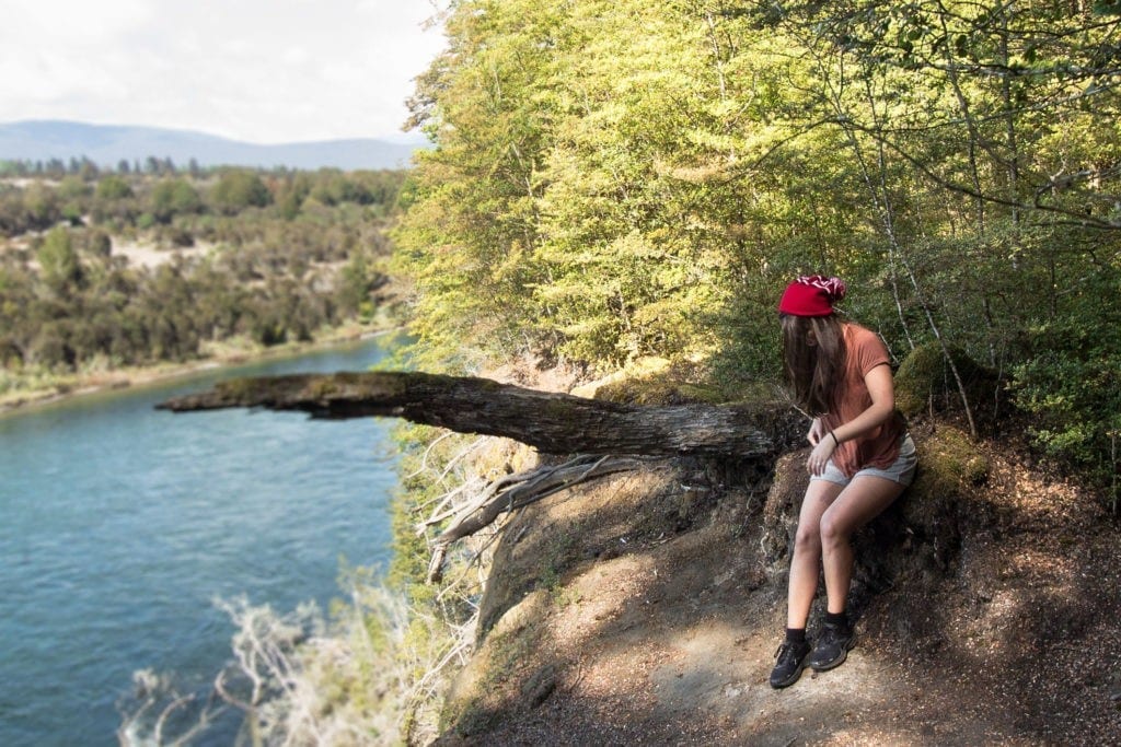 Female sitting on a large tree trunk at Kepler Track, Te Anau