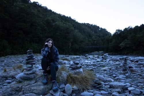 South island road trip: woman sitting on large rocks at Blue Pools Track in Wanaka