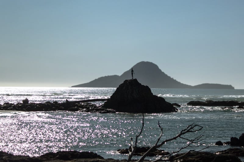 A photo off the coast in Whakatane, Whale island is in the background, the statue 'Lady on the rock' is in the foreground. This is the most iconic view when visiting Whakatane on a New Zealand holiday.