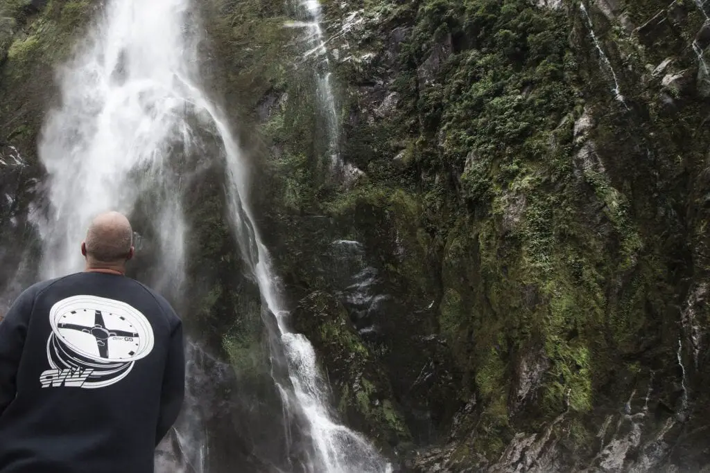 Cruising Milford Sounds - Picture of male standing below waterfall at Milford Sound