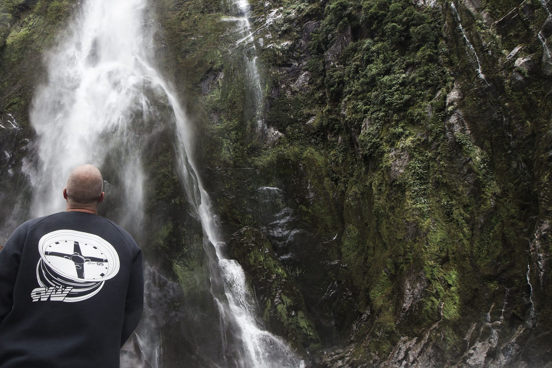Picture of male standing below waterfall at Milford Sound