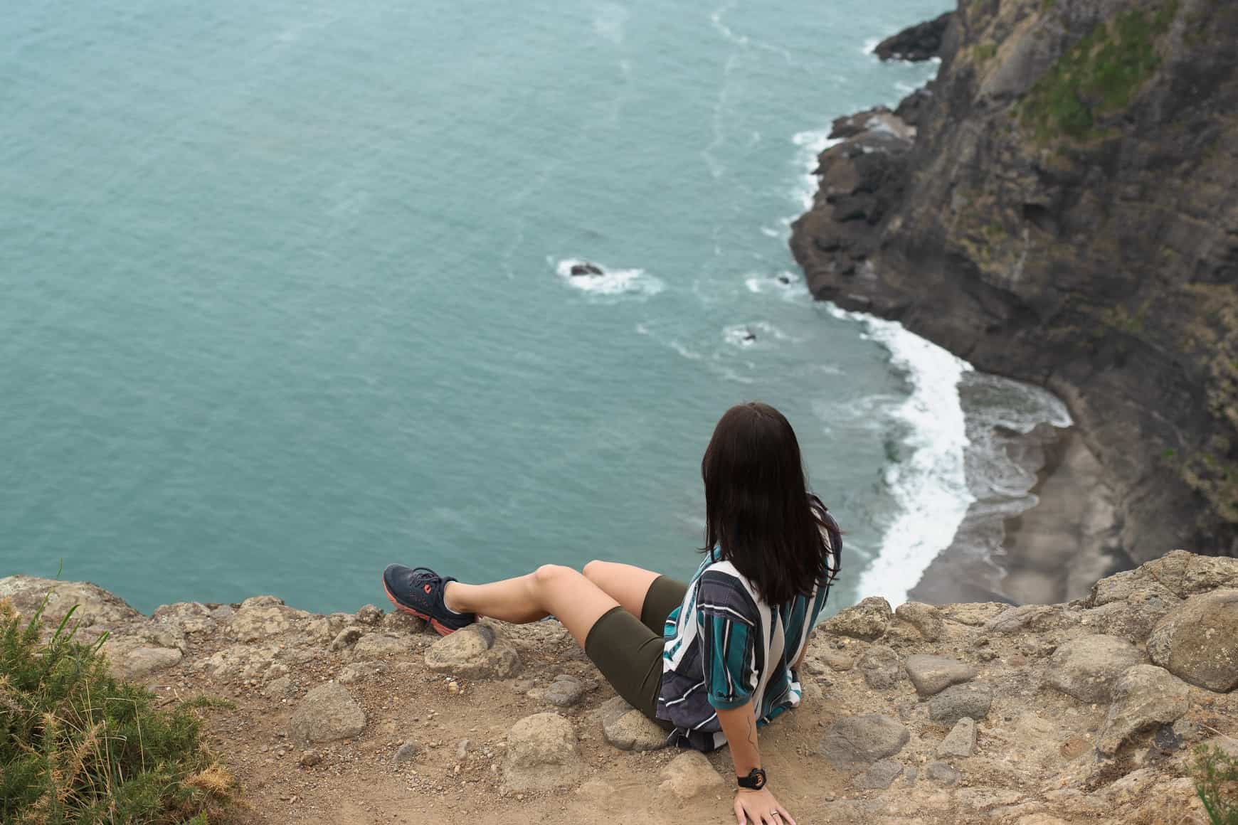 Female sitting on the edge of the cliff at Mercer Bay Loop