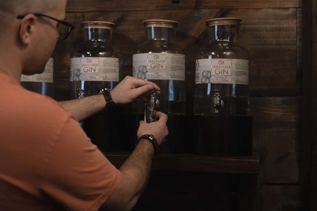 A man pouring shots of gin from large bottles of gin