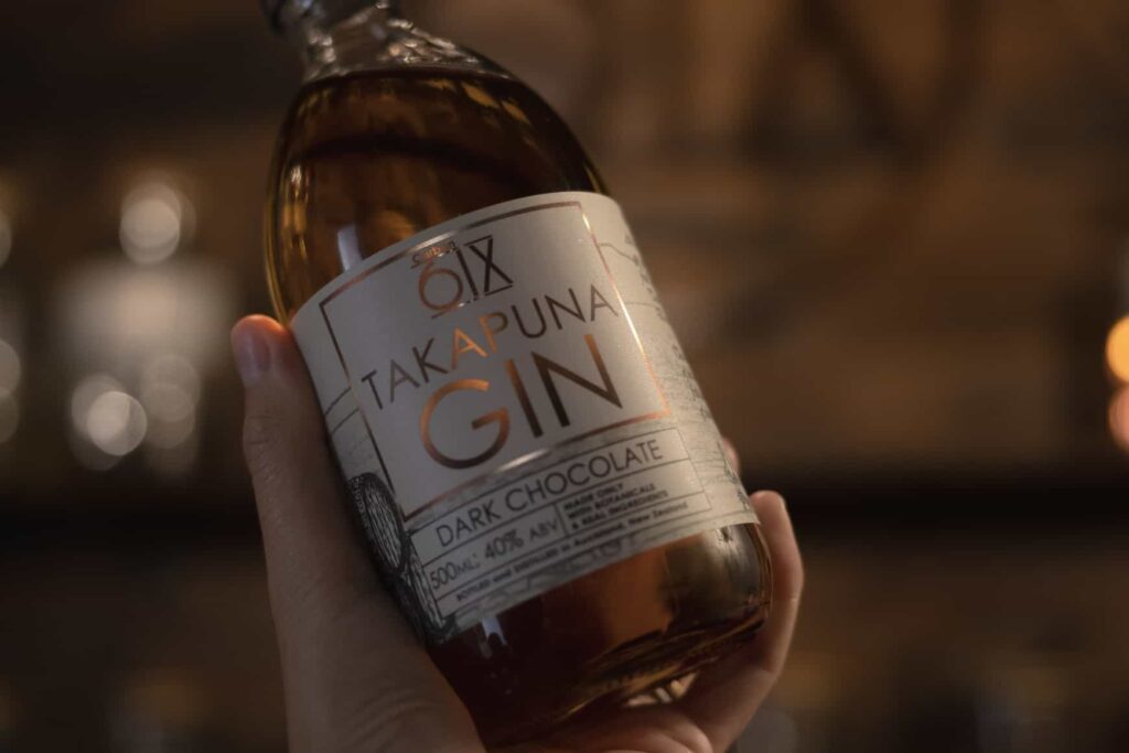 A womans hand holding a bottle of gin at Takapuna gin tasting in Auckland