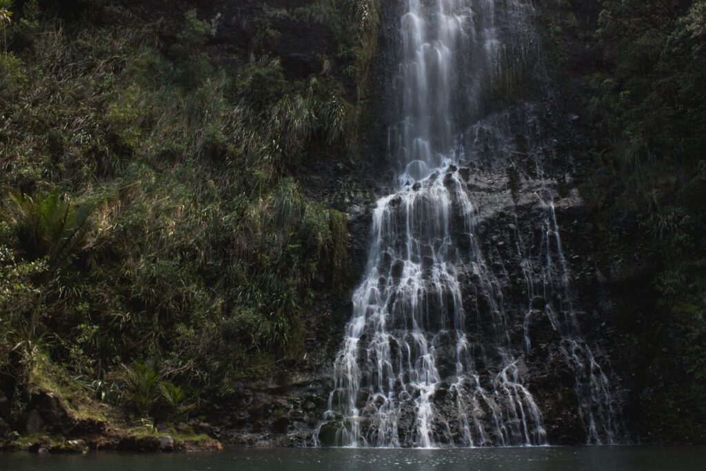 6 of the Best West Auckland Walks 7 A ground level view of Karekare waterfall trickling down the cliff face into the pool below