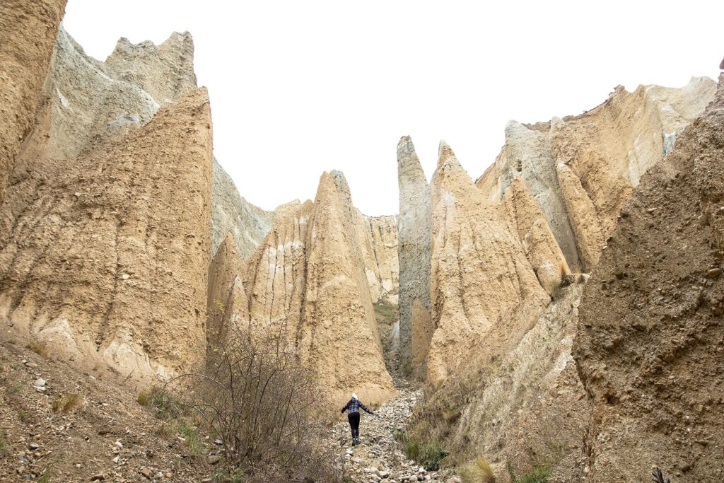 A woman walking up a large rocky mound at Omarama Clay Cliffs