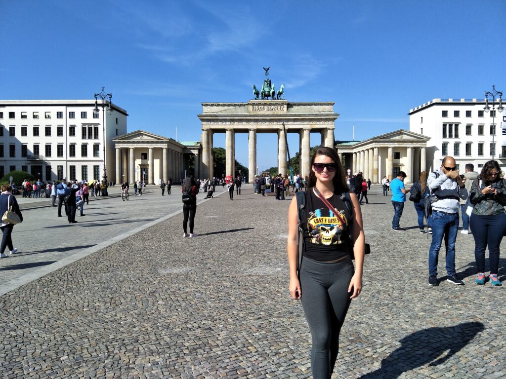 Woman standing infront of a Berlin WWII landmark, Brandenburg Gate. The gate is far back in the distance. This is one of the best things to do in Berlin.