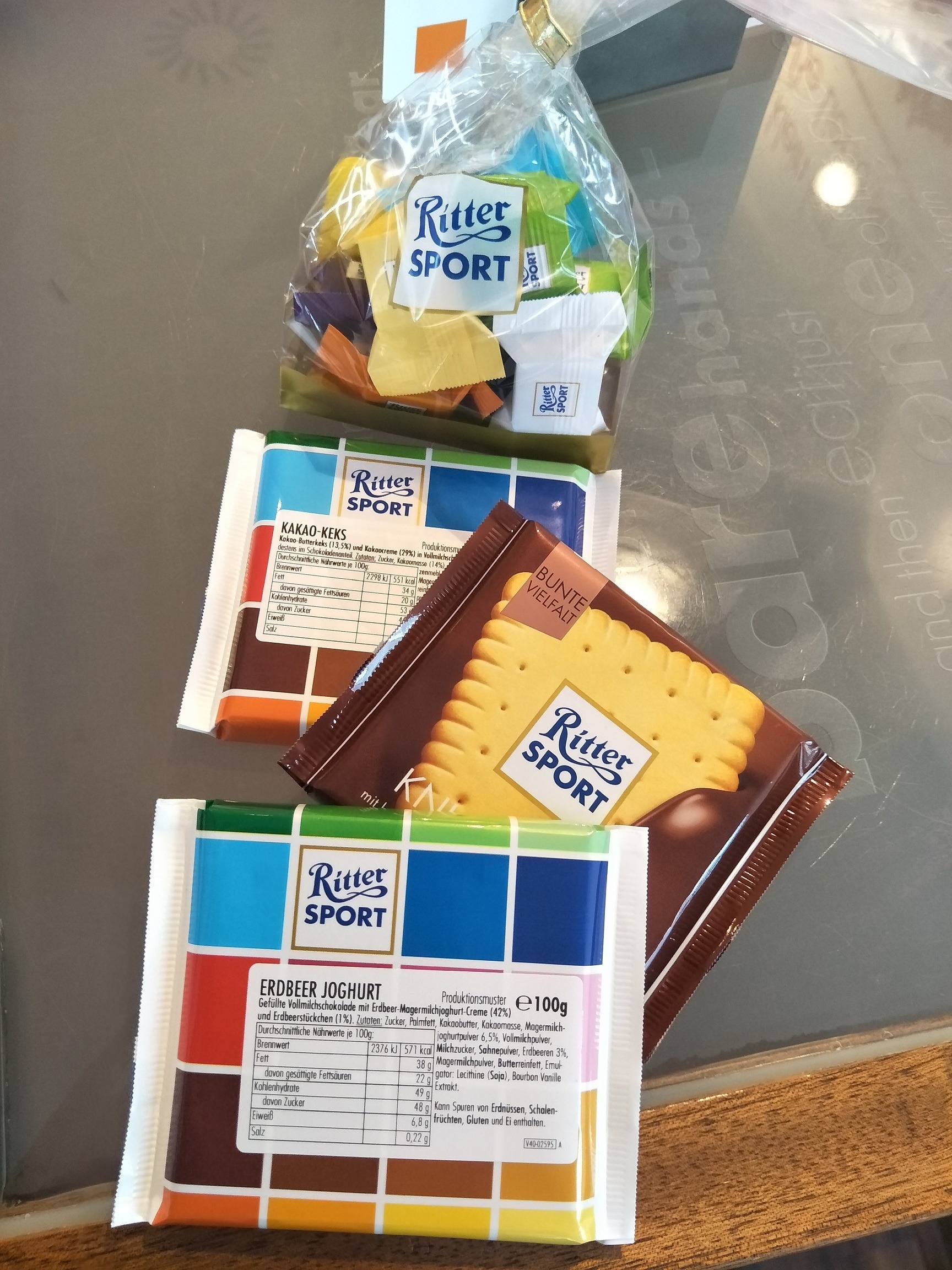 3 different Rittersport chocolate bars and a bag of small Rittersport chocolates lying out on a table