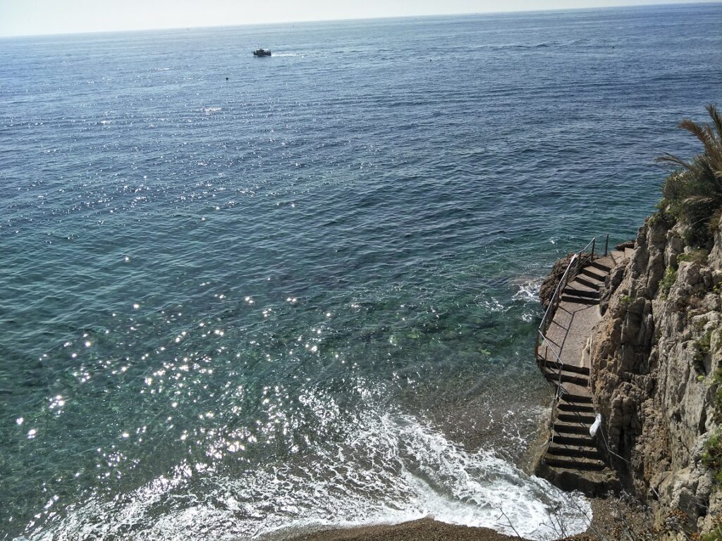 The Best Things to do in Monaco 9 A birds eye view of waves lapping up to a cliff at Monaco beach
