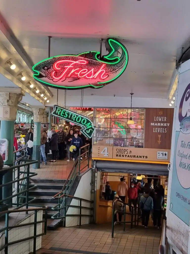 Photo of inside the Pike Place Market. A neon sign of a fish that says 'fresh'