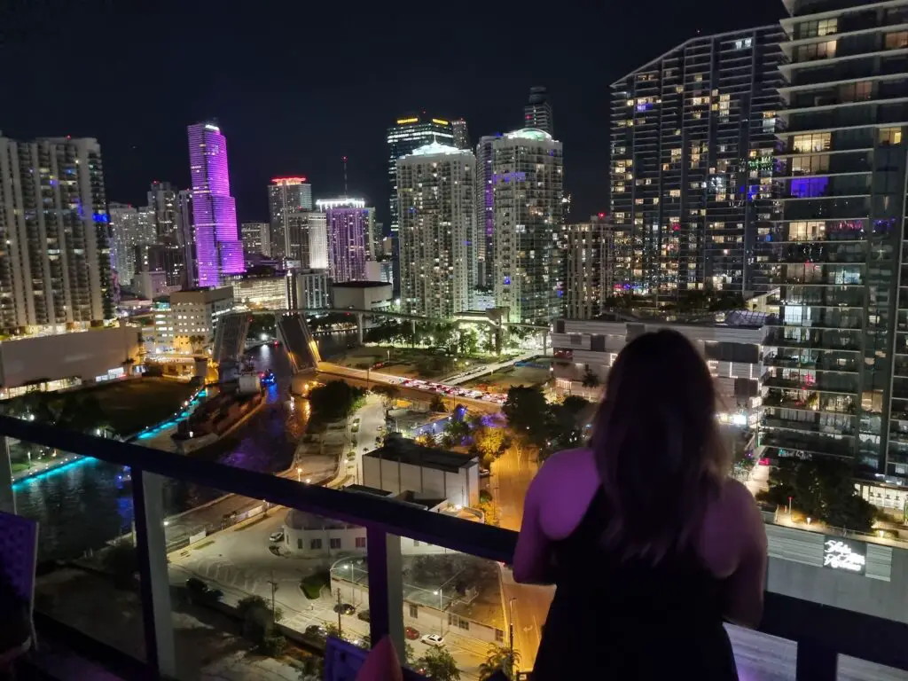 Female overlooking Miami at night from the 22nd floor of a high rise building
