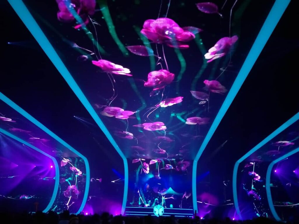 Tomorrowland Belgium: Survival Guide 2025 6 The techno stage at Tomorrowland, the pink and blue flower graphics are prjected onto the ceiling and walls