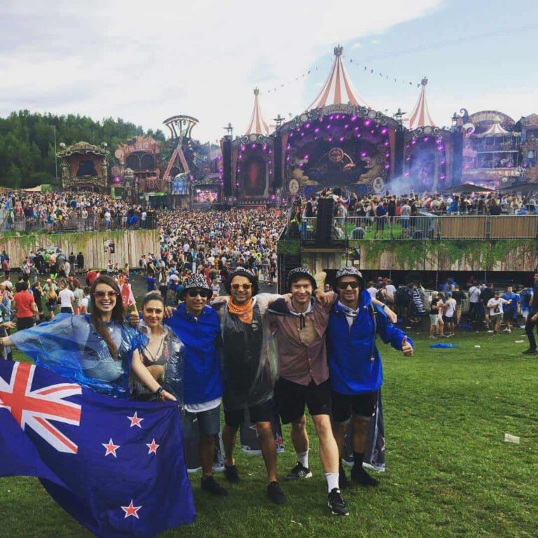A group of people standing together in front of main stage, holding a New Zealand flag at Tomorrowland