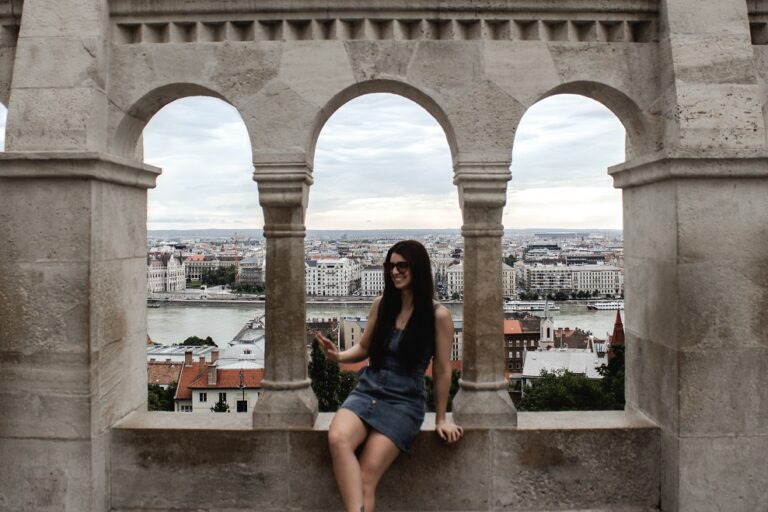 Female sitting in an opening in a stone wall at Fishermans Bastion in Budapest, Hungary