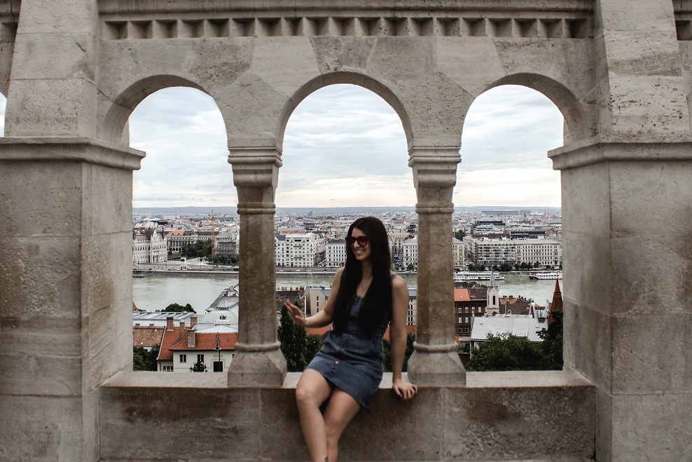 Female sitting in an opening in a stone wall at Fishermans Bastion in Budapest, Hungary