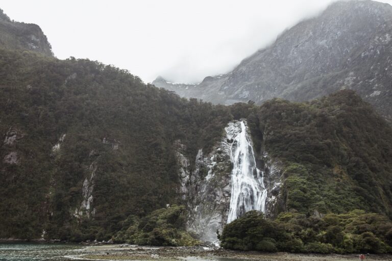 Picture of a waterfall running down a cliff face with another large mountain behind it