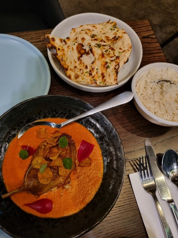 7 of The Best Indian Restaurants in Auckland 6 A bowl of naan bread, a bowl of rice and another bowl filled with an orange duck curry at Cassia Indian restaurant.