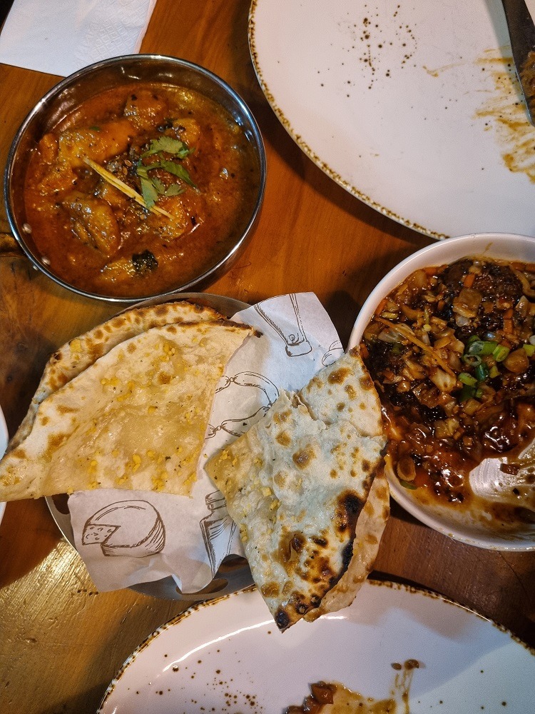 7 of The Best Indian Restaurants in Auckland 2 A picture of 3 Indian meals at Karam eatery in Takapuna. There is a bowl of garlic naan, next to that is a bowl of vege manchurian dumplings in gravy and the third dish is a goan fish curry.