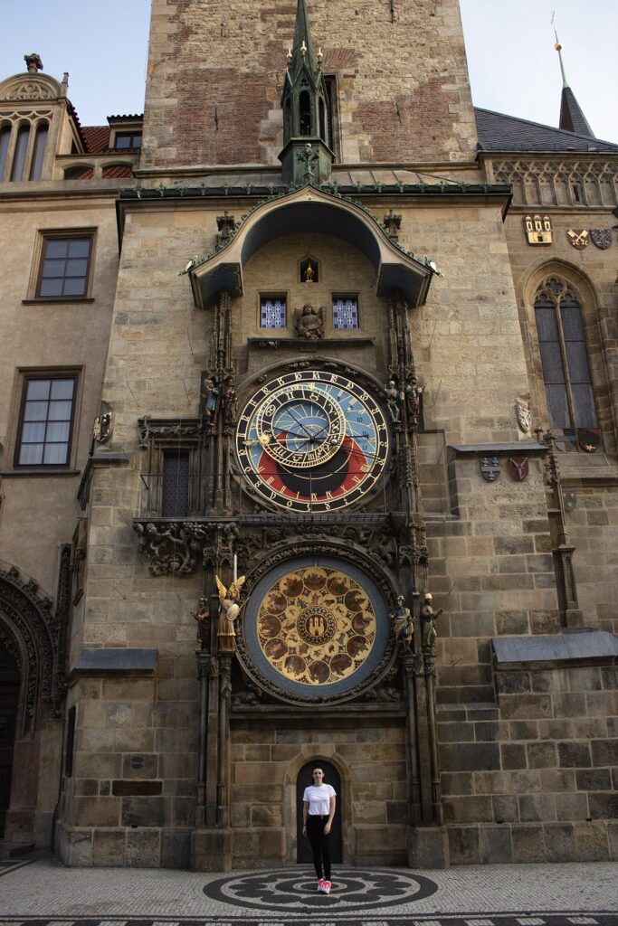 Woman standing alone in front of the Astronomical clock in Prague