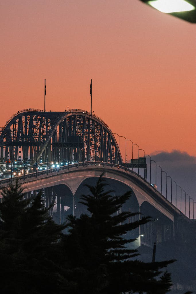 A stunning view of Auckland Harbour Bridge with a warm sunrise backdrop.