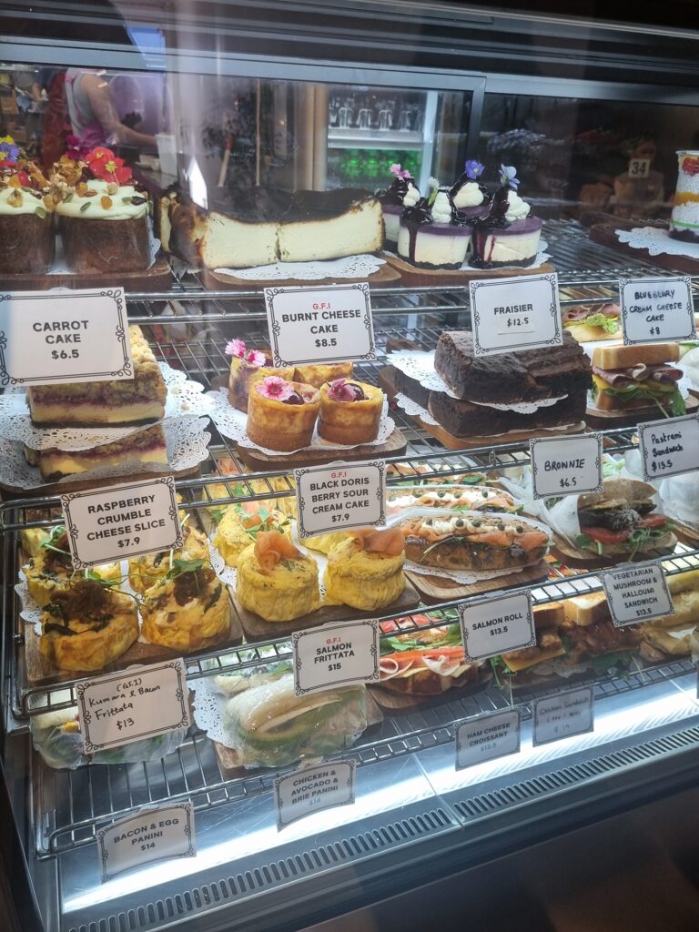 This photo shows sweat treats and savoury food in the cabinet at one of the best dog-friendly cafes in Auckland. Dear Friends in Milford.