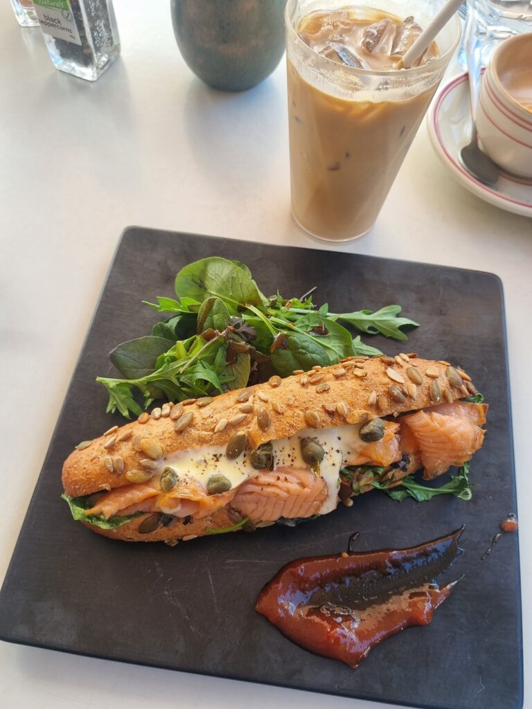 This image shows a filled bread roll with salmon and salad at Dear Friends cafe in Milford.