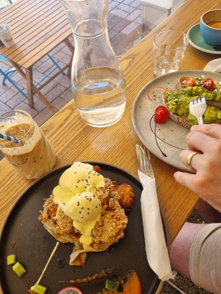 Two plates of food from Beam cafe. One plate has the avocado mash with cherry tomatos, the other plate has the chicken eggs benedict