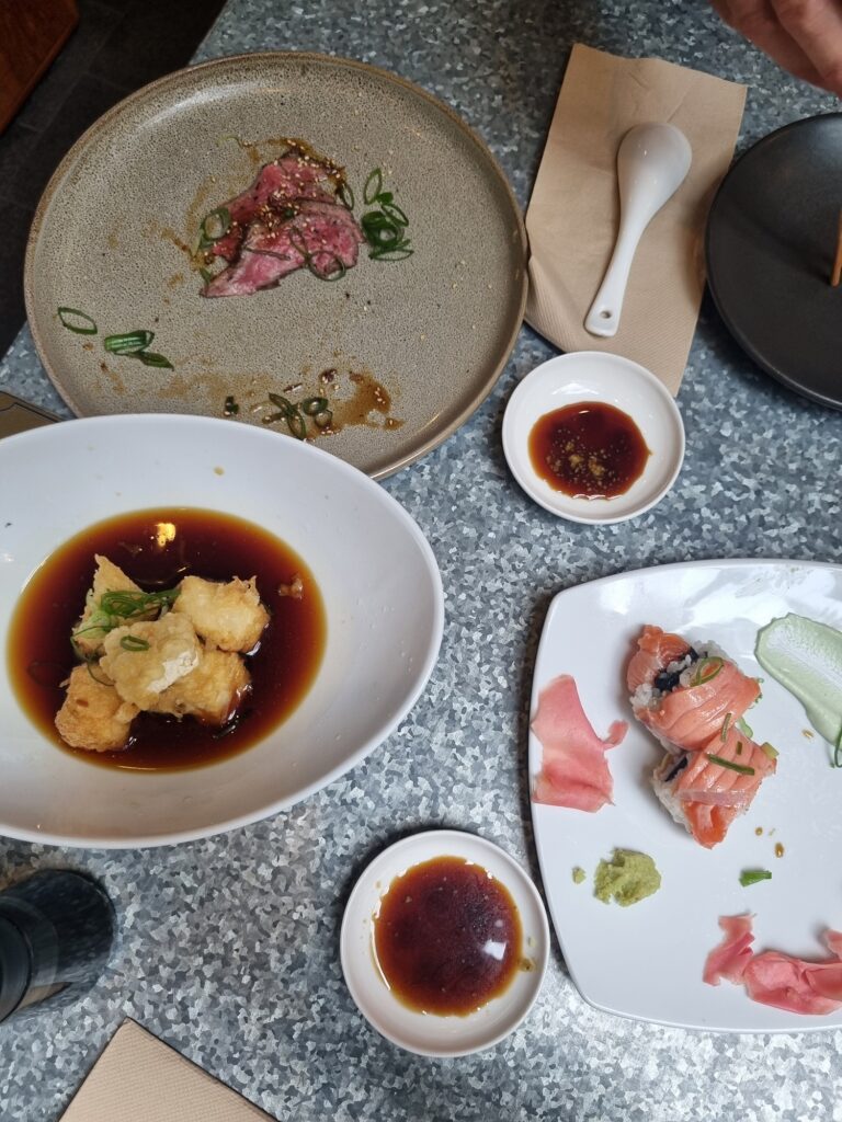 Authentic Japanese Food in Auckland: Mad Samurai Restaurant. This image shows half empty plates of beef tataki, agadashi tofu and salmon sushi roll.
