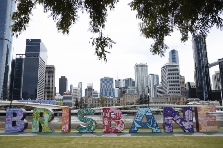A large colourful 'Brisbane' sign in South Bank. Behind the sign is the city scape of Brisbane CBD.