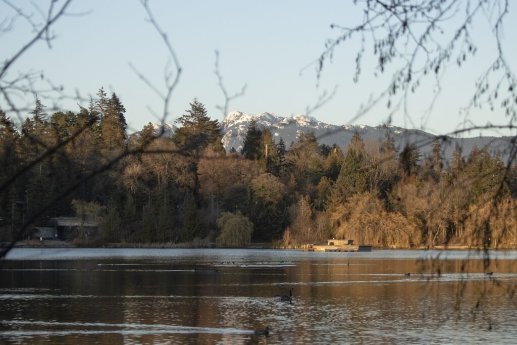 Vancouver Travel Guide: A view of snowcapped mountains from across the lake in Stanley Park in Vancouver