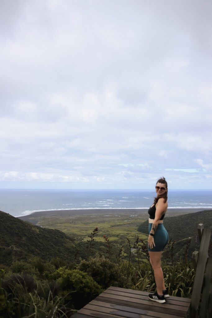 Hiking Omanawanui Track: A Must-Do Auckland Hike Day hikes in Auckland: Woman standing on top of a wooden staircase overlooking the ridge along Omanawanui track in Auckland